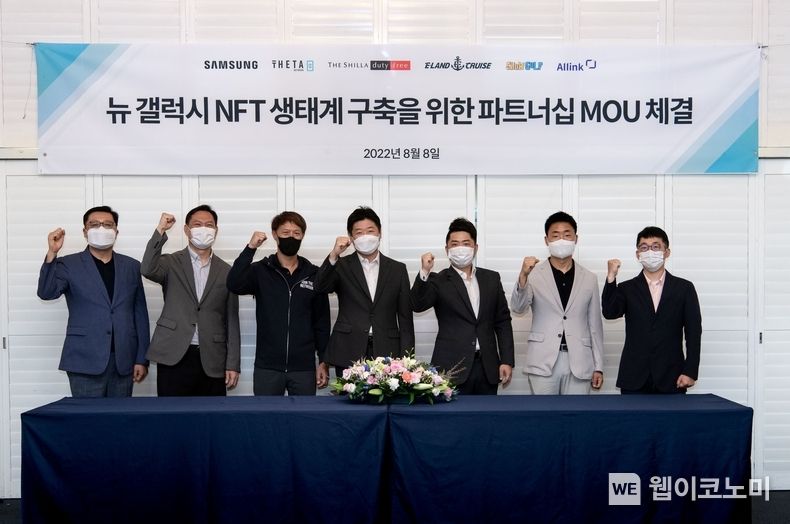 "갤럭시 NFT 생태계 구축을 위한 파트너쉽 MOU 체결식" <br>
<br>
좌측부터 최상진 B2B그룹장(삼성전자판매), 이신우 프로(삼성전자 한국총괄), 미치리우 CEO(쎄타랩스) 정동성 부점장(신라면세점), 박동진 대표(이크루즈), 홍성환 본부장(쇼골프), 김경동 대표(올링크) 2022.08.08 (출처: 삼성전자) 