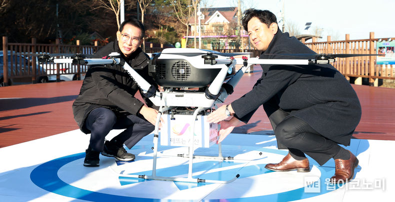 윤진호 교촌에프앤비㈜ 대표이사(오른쪽)와 이완섭 서산시장이 섬 지역 배송을 위해 드론에 교촌치킨을 넣고 있다. 2022.12.09 (출처:교촌에프앤비(주))