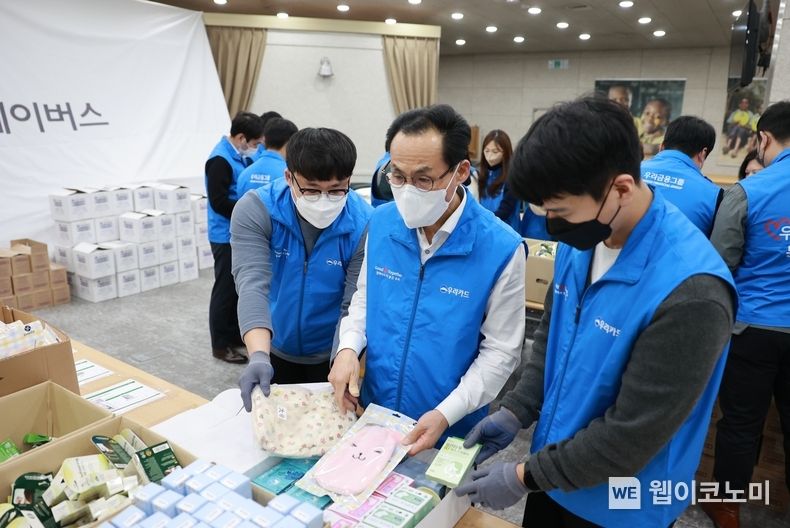 이달 26일 영등포구에 위치한 굿네이버스 본부에서 우리카드 김정기 사장(가운데 흰색 셔츠, 파란색 조끼)과 임직원들이 생리대 키트를 직접 포장하고 있다. 2022.12.30 (출처:우리카드)