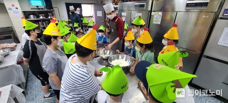 BBQ 치킨대학의 치킨캠프에 참여한 아이들이 황금올리브 치킨 조리하는 방법을 설명 듣고 있다. 2023.02.09 (출처:제너시스BBQ)