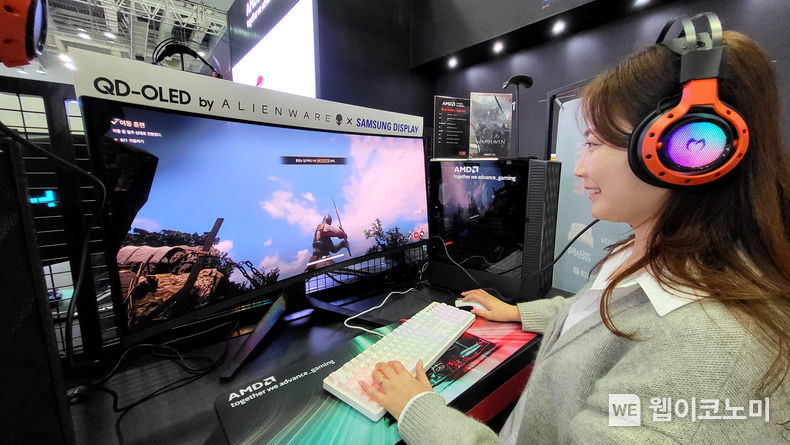 삼성디스플레이 모델이 지스타 2023 AMD 부스에 전시된 '에일리언웨어 34 커브드 QD-OLED 게이밍 모니터'로 대규모 이용자 간 대전 '워헤이븐'을 체험해보고 있다. 2023.11.16. (출처: 삼성디스플레이)