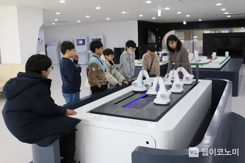 웹젠의 ‘Let’s PLAY 코딩!’에 참여한 초등학교 고학년 임직원 자녀들이 ‘스마트 팩토리’ 원리 설명을 듣고 있다 / 2023.12.05 (출처: 웹젠)