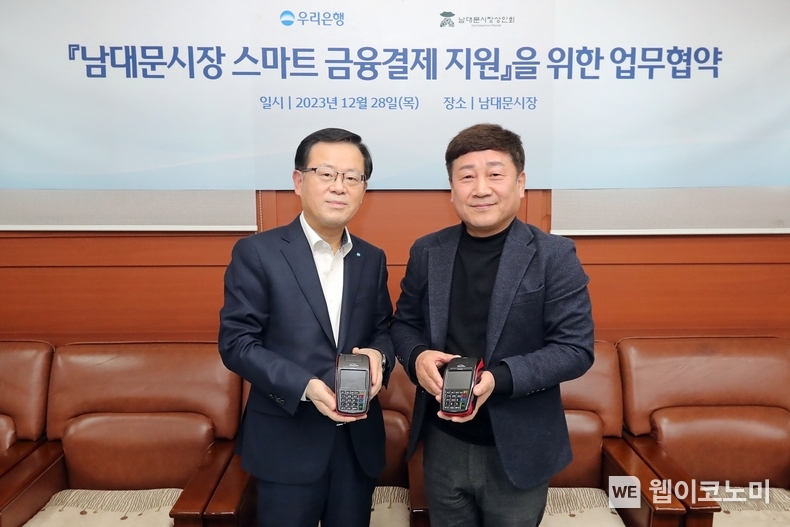 우리은행(은행장 조병규)은 민생금융지원방안 중 자율프로그램의 일환으로 지난 28일 남대문시장 상인회와 ‘상생경영 및 동반성장을 위한 협약’을 체결하고 스마트 결제기기 지원을 통해 남대문시장 스마트 결제 인프라 구축을 지원하기로 했다. 왼쪽부터 조병규 우리은행장과 문남엽 상인회 회장이 기념촬영을 하고 있다. / 2023.12.29 (출처: 우리은행)