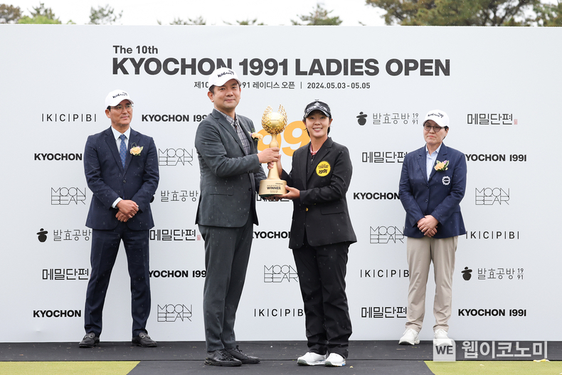 지난 5일(일) 열린 한국여자프로골프(KLPGA) 투어 ‘제10회 교촌 1991 레이디스 오픈’ 시상식에서 윤진호 교촌에프앤비㈜ 국내사업지원부문 부문장이 ‘제10회 교촌 1991 레이디스 오픈’에서 우승을 차지한 박지영 선수와 우승 트로피를 들고 기념사진 촬영을 하고 있는 모습 / 2024.05.07 (출처: 교촌에프앤비)