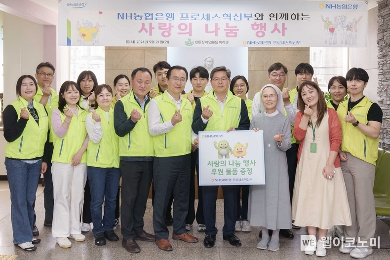 NH농협은행은 21일 서울 성동구 소재 성동장애인복지관을 방문해 후원물품 전달 및 봉사활동을 실시했다. 최성자 성동장애인종합복지관 관장(푯말 든 오른쪽)과 정재호 디지털전략사업부문 부행장(푯말 든 왼쪽) 및 농협은행 프로세스혁신부 직원들이 기념사진을 촬영하고 있다. / 2024.05.21 (출처: NH농협은행)