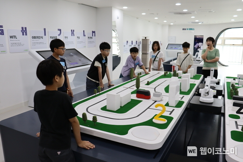 웹젠의 ‘Let’s PLAY 코딩!’에 참여한 초등학교 고학년 임직원 자녀들이 ‘AI 자율주행’ 원리 설명을 듣고 있다. / 2024.07.22 (출처: 웹젠)