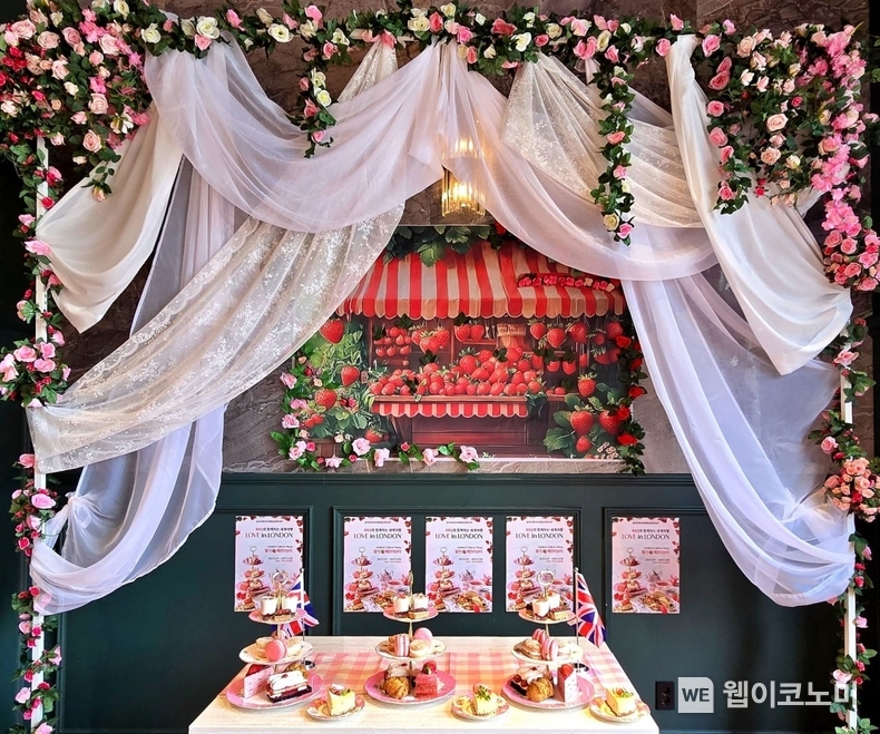 BBQ빌리지 송리단길점 포토존의 ‘러브 인 런던’ 프로모션 메뉴 아이템 ‘심플 딸기 애프터눈티 세트’ 구성품 3단 디저트 트레이와 선택 메뉴 ‘카라멜 리큐르 치즈케이크’ / 2025.02.04 (출처: 제너시스BBQ)