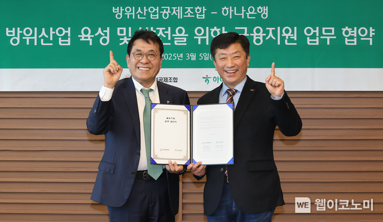 하나은행은 5일 방위산업공제조합과 K-방위산업의 육성 및 금융 지원을 위한 업무협약을 체결했다. 이날 협약식에 참석한 김진우 하나은행 중앙영업그룹 부행장(사진 왼쪽)이 김희철 방위산업공제조합 상근부이사장(사진 오른쪽)과 협약서를 들고 기념촬영을 하고 있다. / 2025.03.05 (출처: 하나은행)
