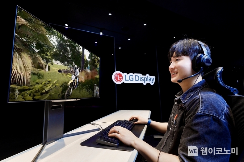 LG디스플레이 모델이 4세대 기술이 적용된 27인치 OLED 모니터 패널로 게임을 즐기고 있다. (출처: LG디스플레이) / 2025. 06. 27